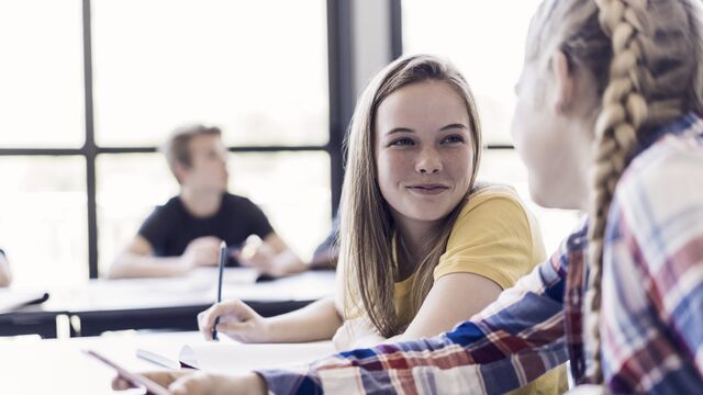 Female friends talking in classroom - small
